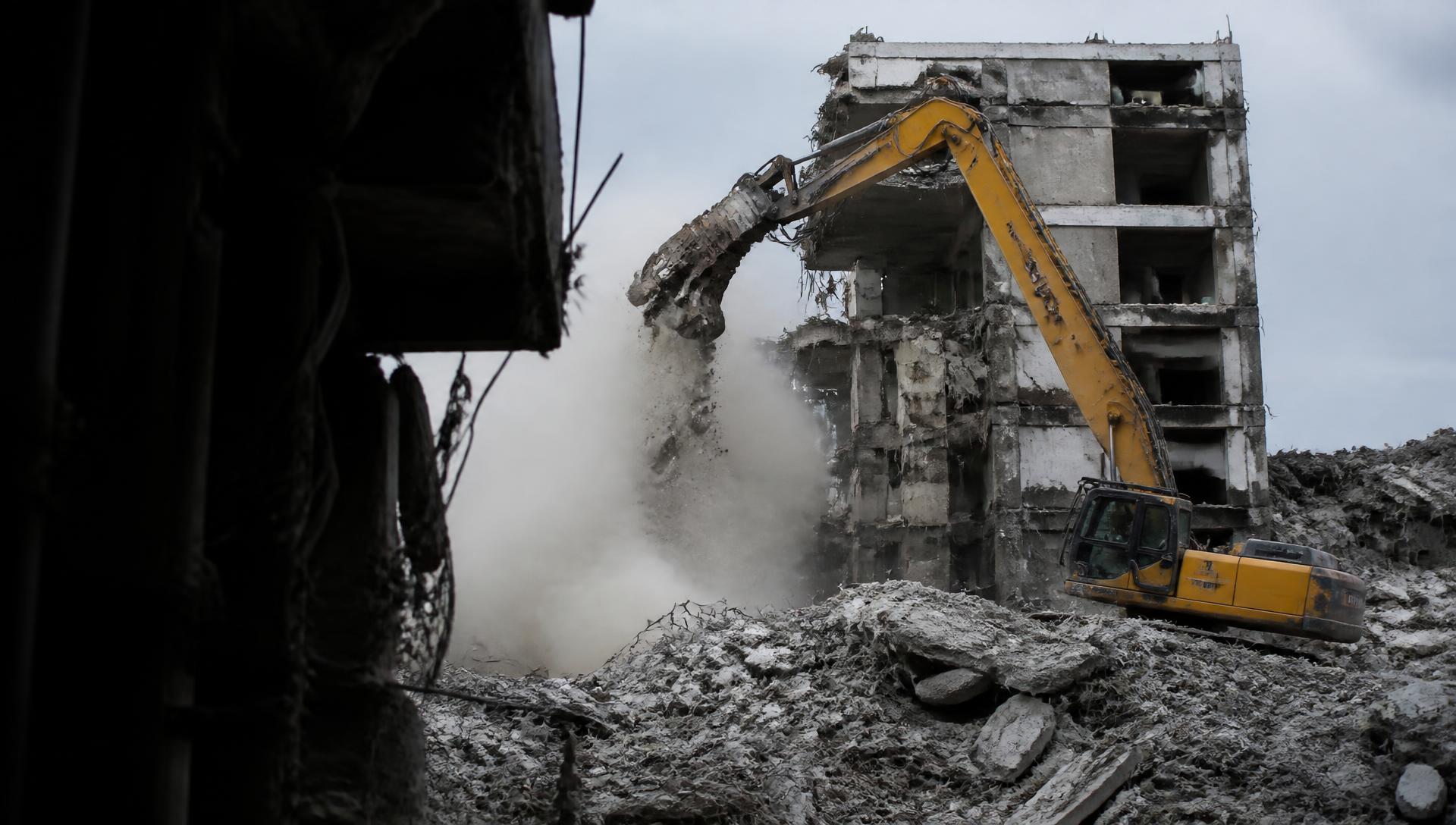 Excavator demolishing a concrete structure on an active jobsite